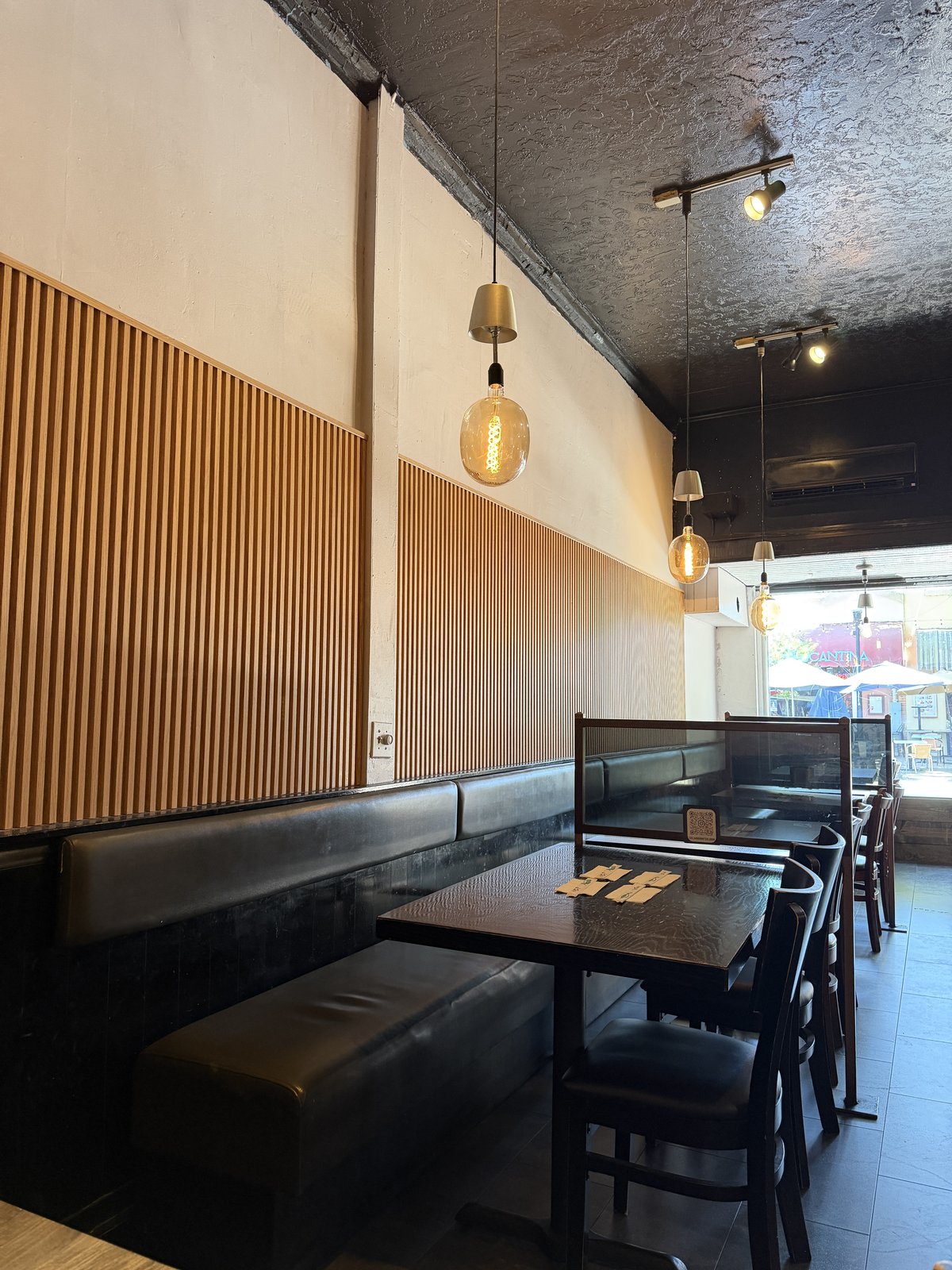 Zen's calm udon shop interior with light wood slat walls, bench seating, and warm Edison-bulb lighting